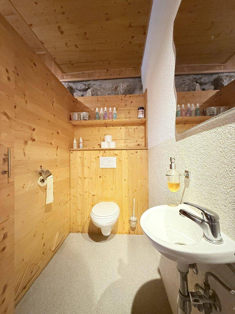 Einfaches WC mit Holzverkleidung und Waschbecken im Wellnessbereich.