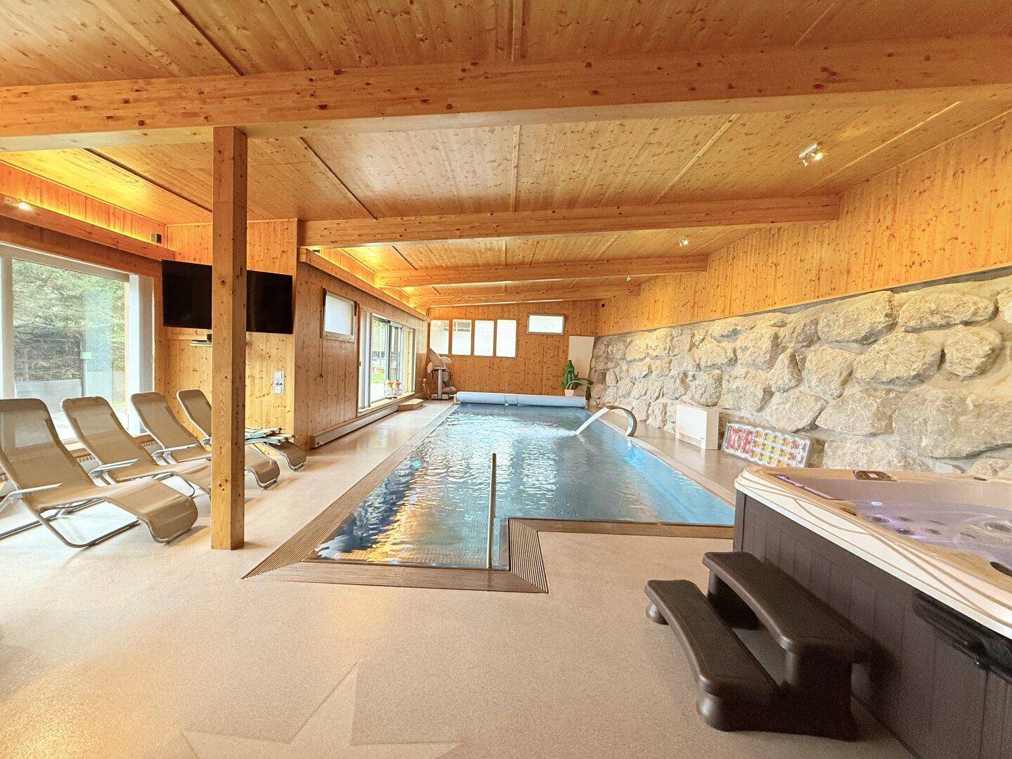 Großzügiger Wellnessbereich mit Innenpool, Whirlpool und Liegestühlen für Entspannung.