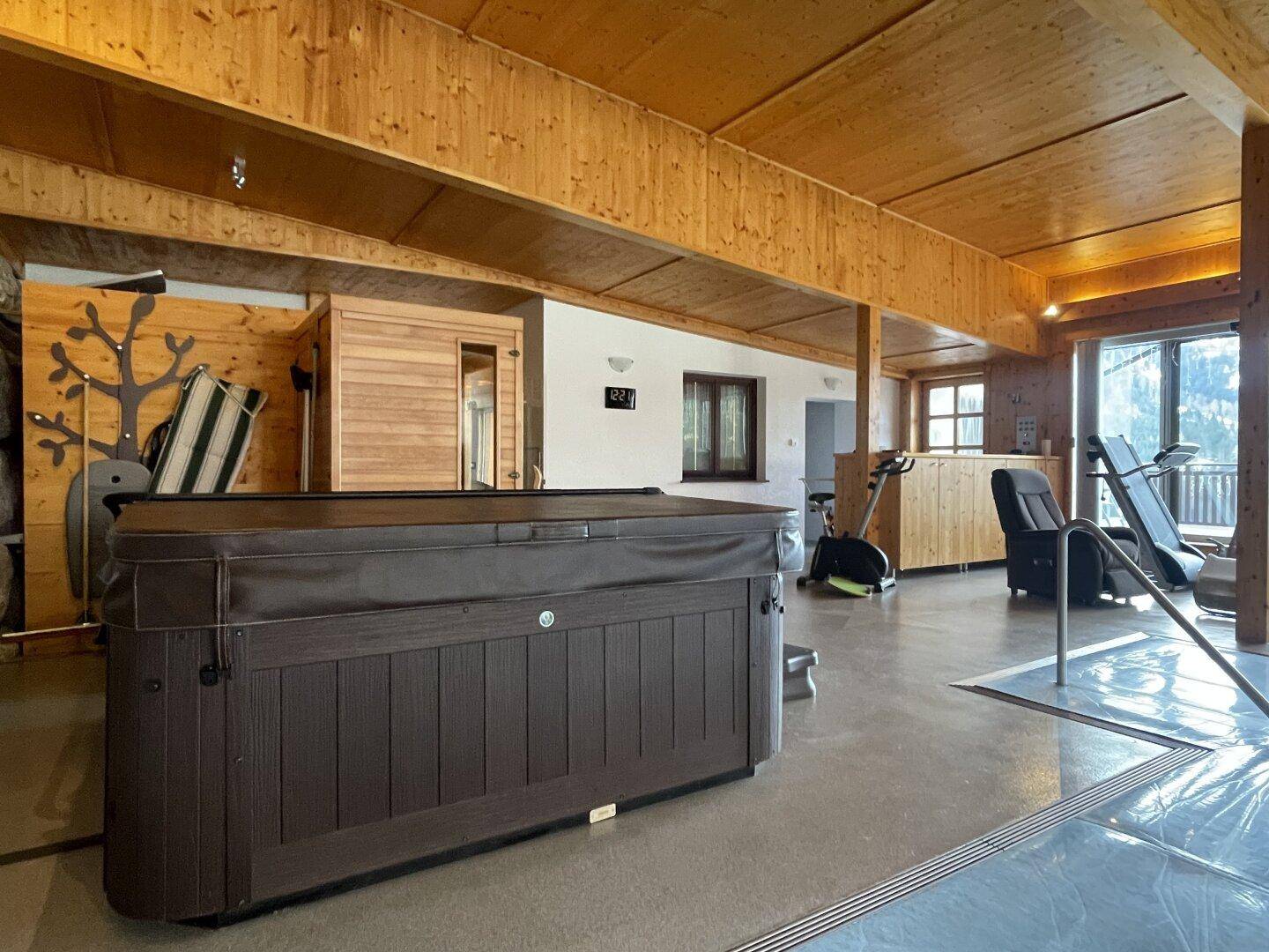 Geräumiger Wellnessbereich mit Whirlpool, Sauna und Fitnessgeräten für Sport und Entspannung.