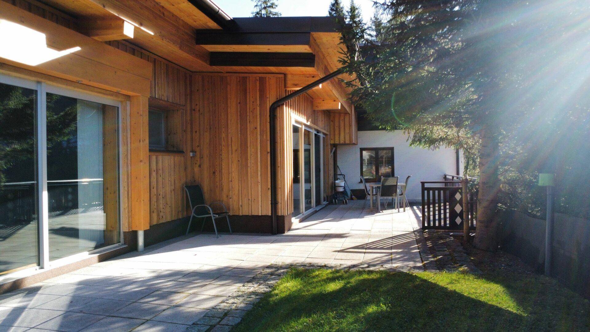 Sonnige Terrasse mit Gartenmöbeln und Zugang zum Rasenbereich des Hauses.