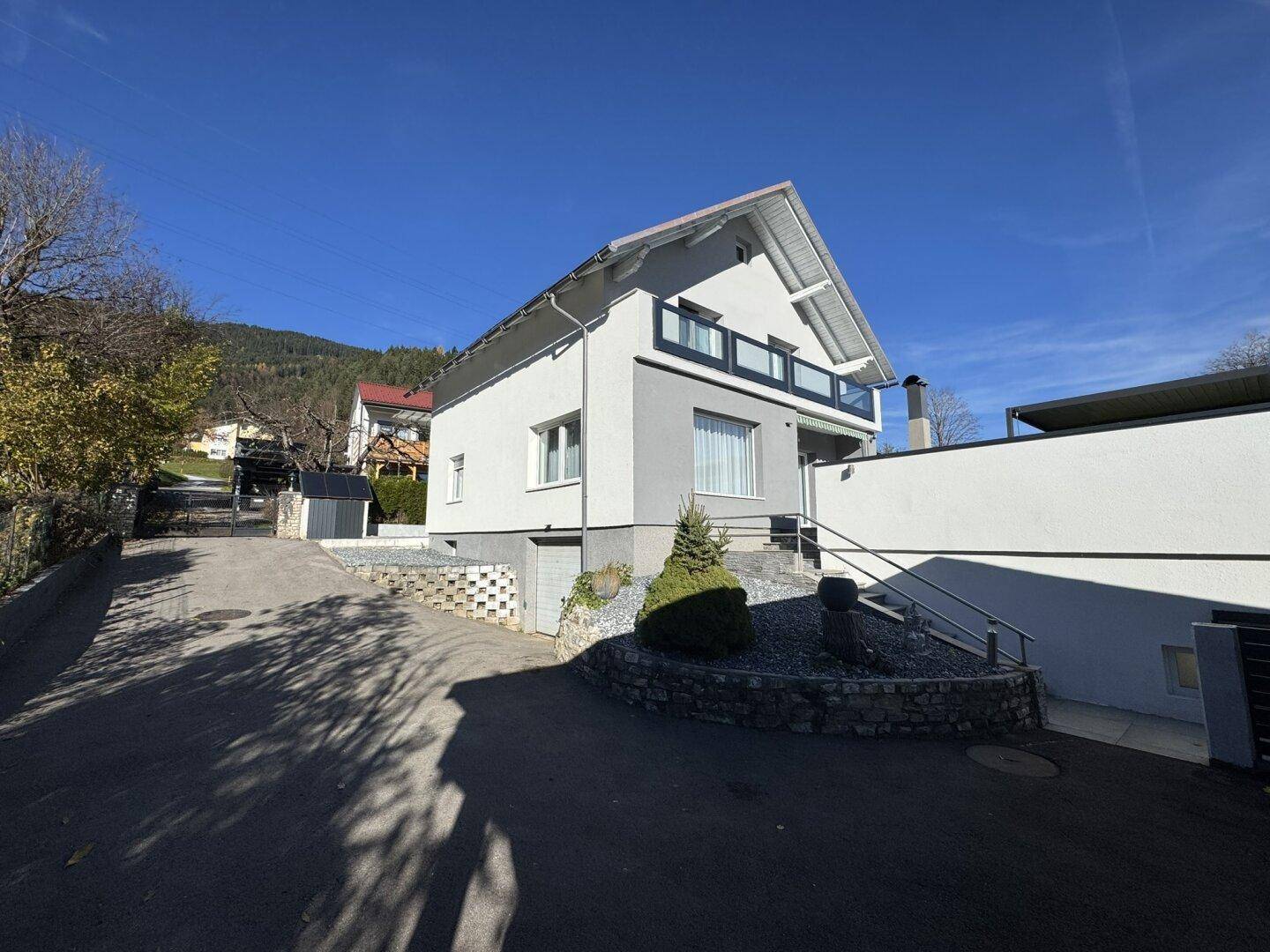 Seitenansicht des modernen Hauses mit Zufahrt, Garage und gepflegter Bepflanzung.