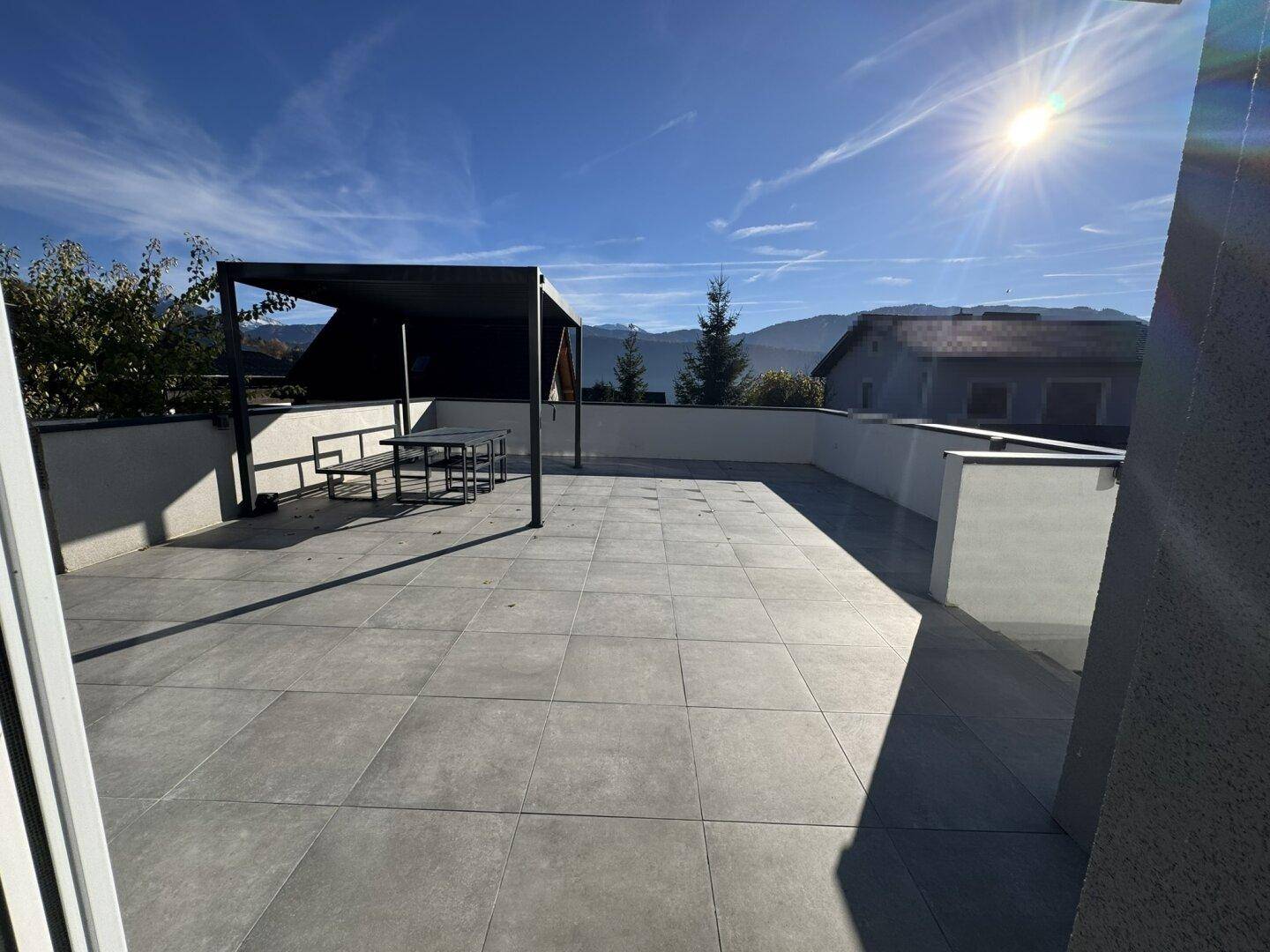 Weitläufige Sonnenterrasse mit Pergola und Essbereich, bietet einen schönen Blick auf die Berge.