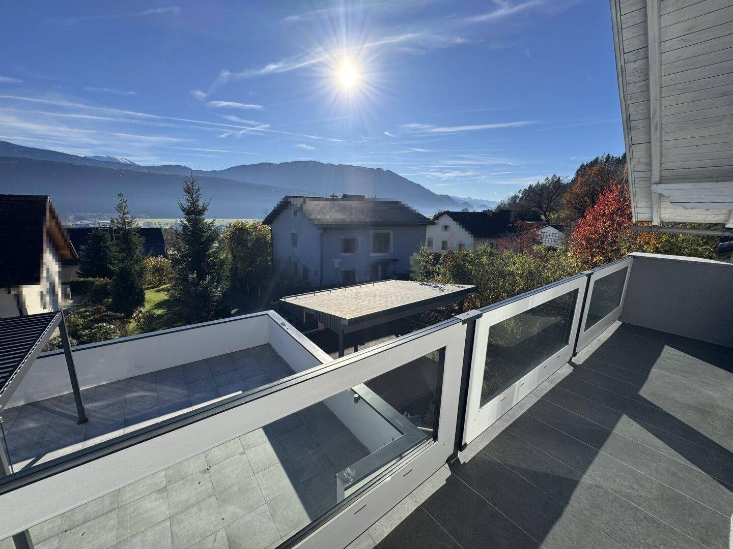 Balkon mit Glasgeländer bietet einen weiten Blick über die Terrasse und die Berglandschaft.