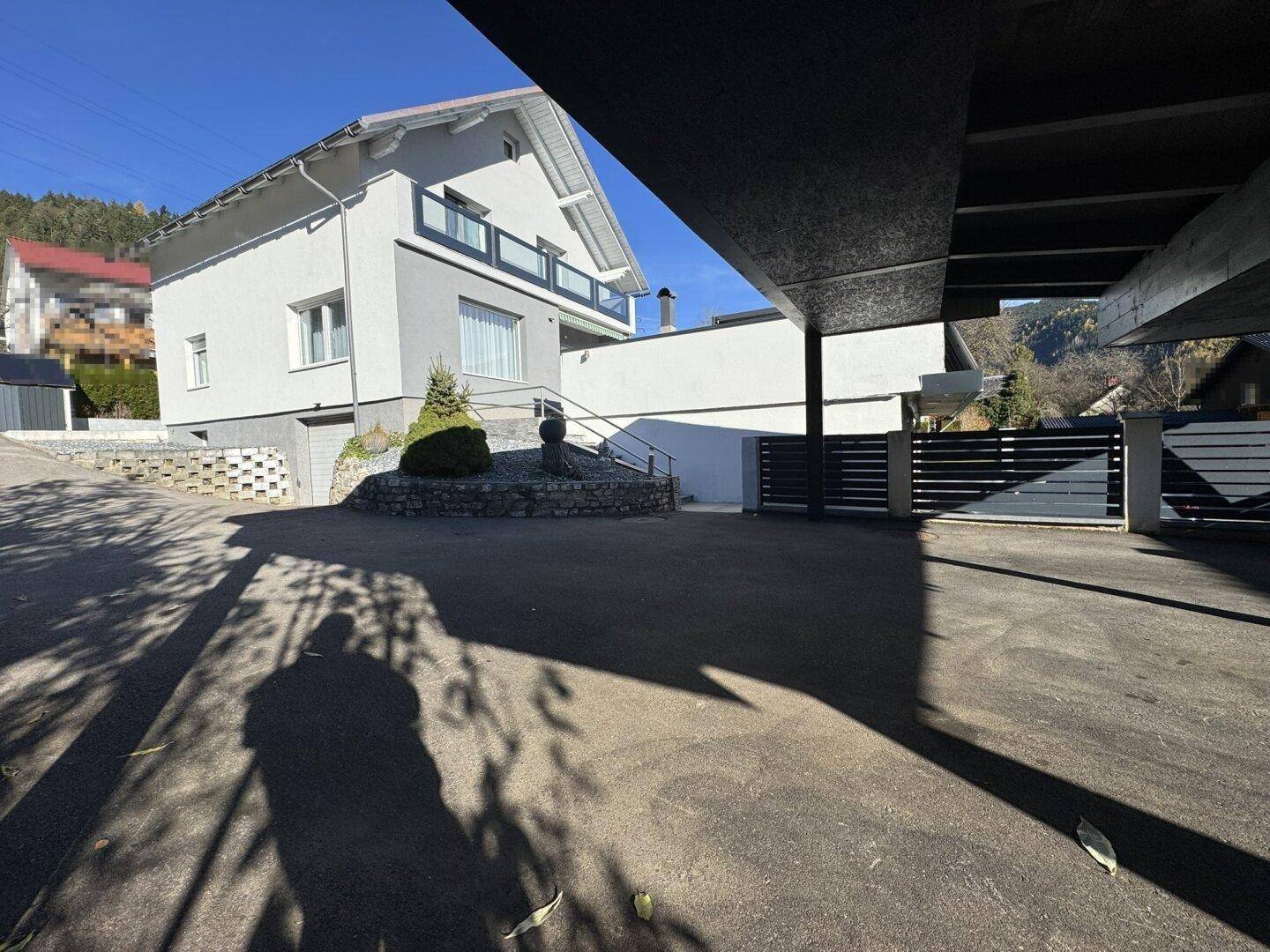 Geräumige Zufahrt zum Haus mit überdachtem Bereich, bietet Schutz für Fahrzeuge.