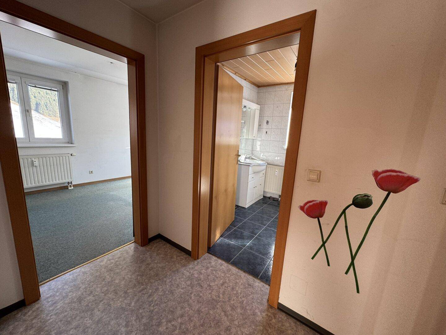 Flur mit Vinylboden und Holztüren, der zu den verschiedenen Zimmern der Wohnung führt.