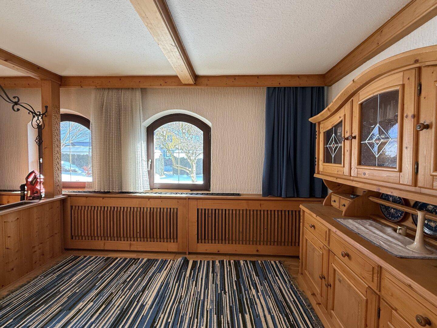Helle Ecke des Essbereichs mit traditionellem Holzschrank und Fenstern mit Blick nach draußen.