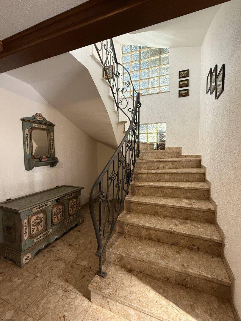 Elegante Steintreppe mit schmiedeeisernem Geländer und Glasbausteinen für natürliches Licht.