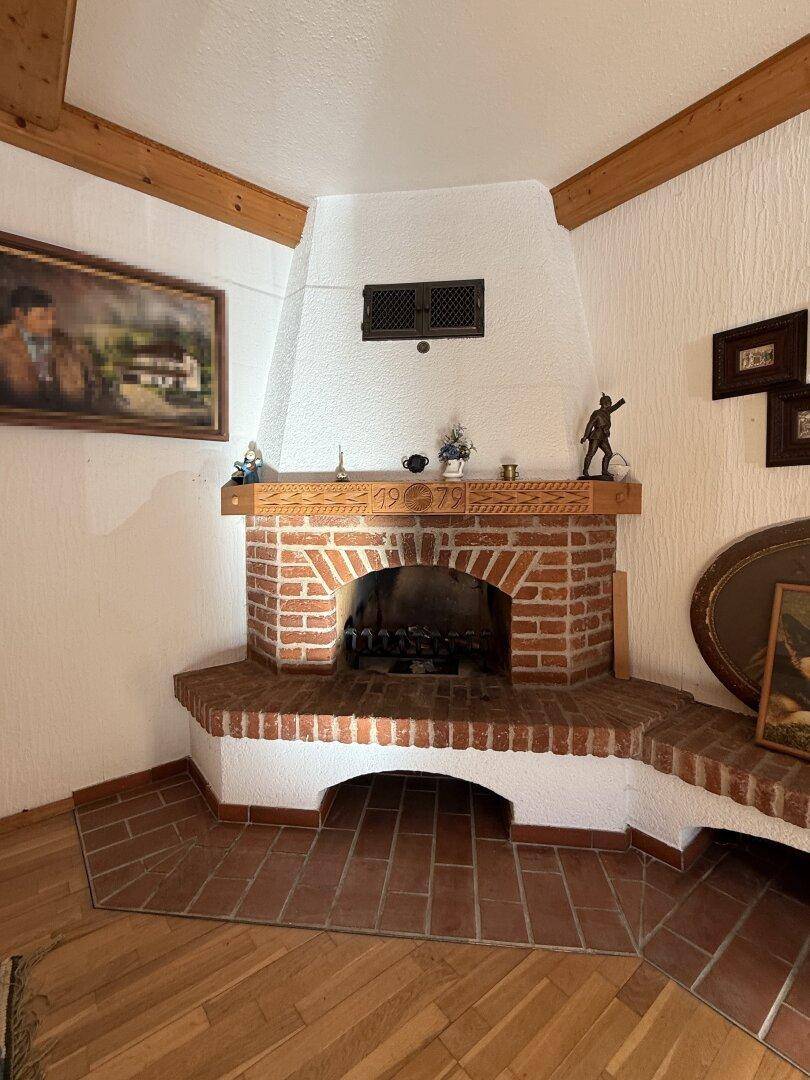 Detailansicht eines traditionellen gemauerten Kamins mit Holzbalken und rustikaler Dekoration.