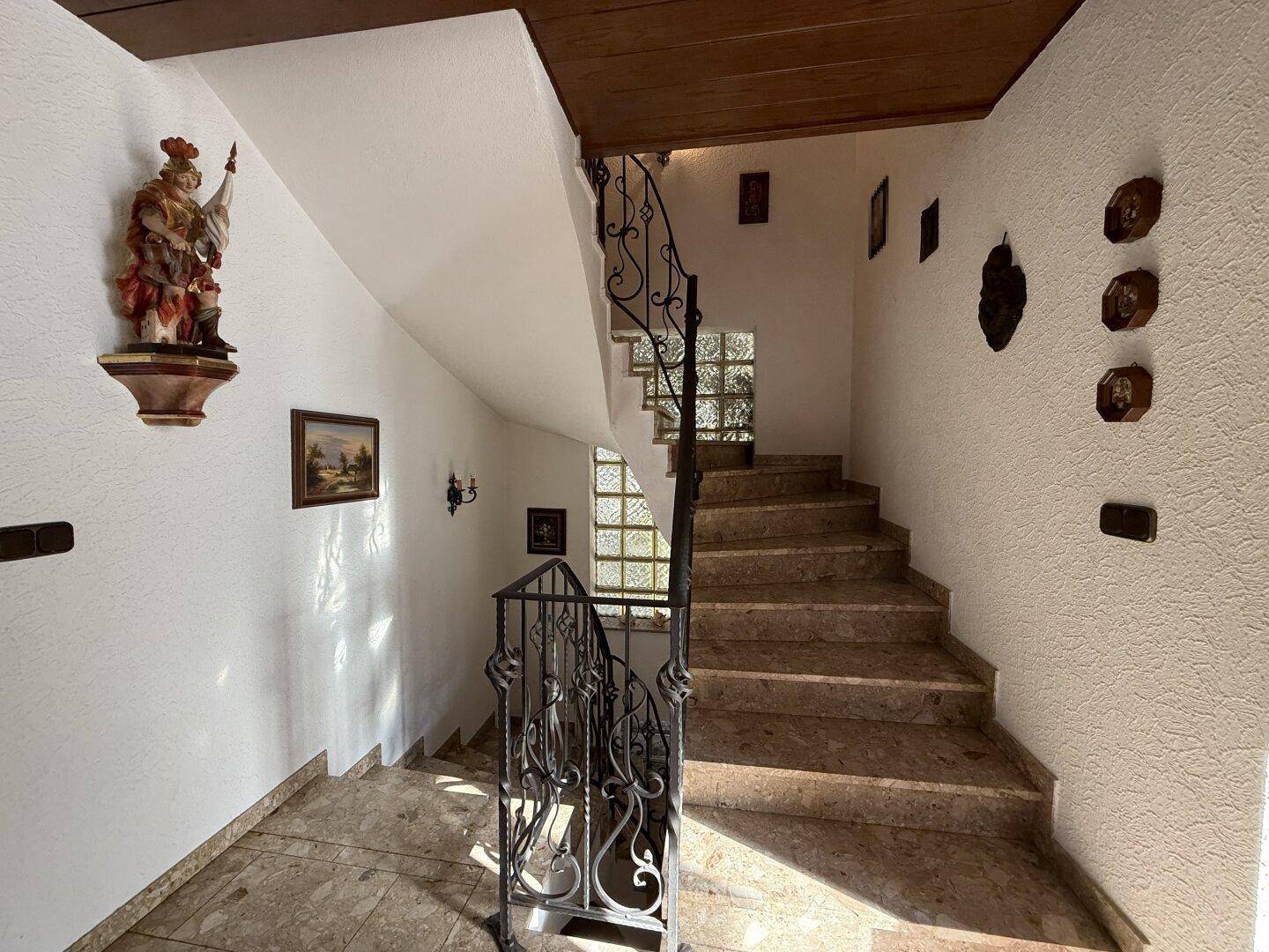 Geräumiges Treppenhaus mit Steinstufen, schmiedeeisernem Geländer und traditioneller Dekoration.