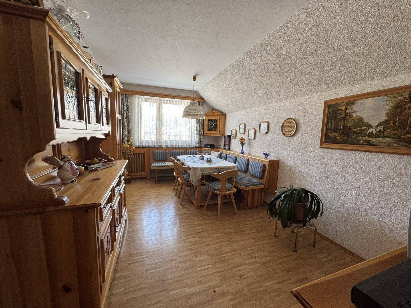 Traditioneller Essbereich mit viel Holz, einem großen Fenster und Blick auf die verschneite Landschaft.