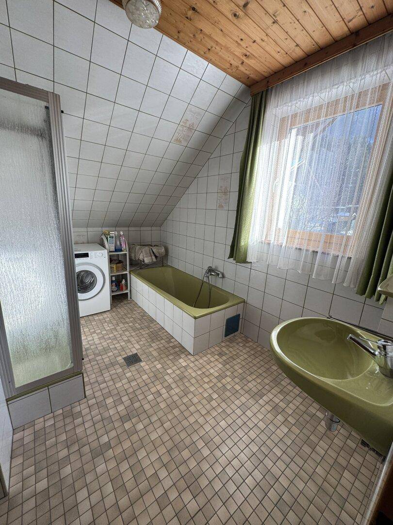 Badezimmer im Stil der 80er Jahre mit grünen Sanitärobjekten, Fliesen und einer Dachschräge.