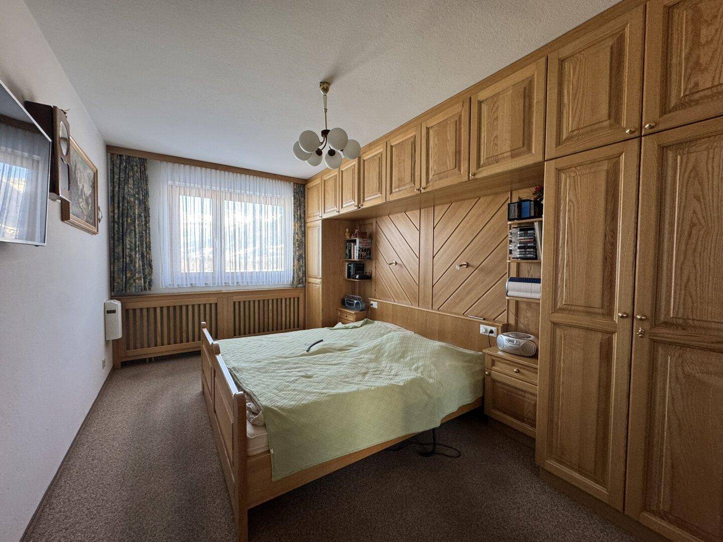 Schlafzimmer mit maßgefertigten Einbauschränken aus hellem Holz und einem gemütlichen Teppichboden.