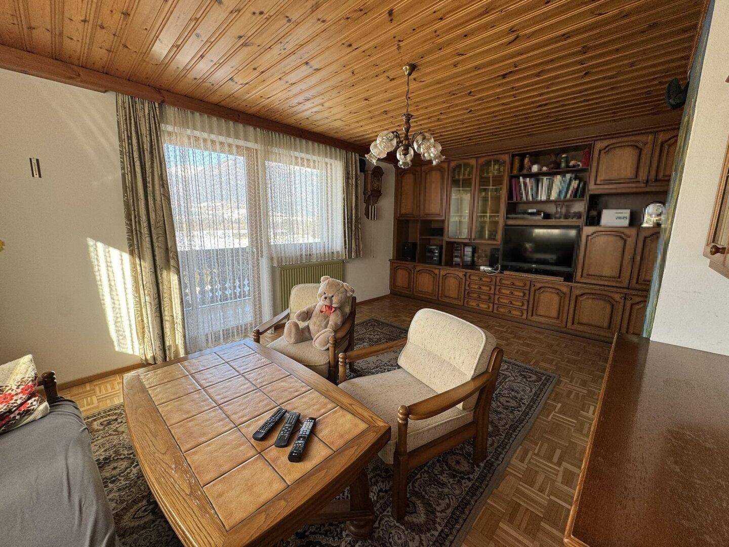 Wohnzimmer mit Holzdecke, Parkettboden und traditionellen Möbeln, hell durch große Fenster.