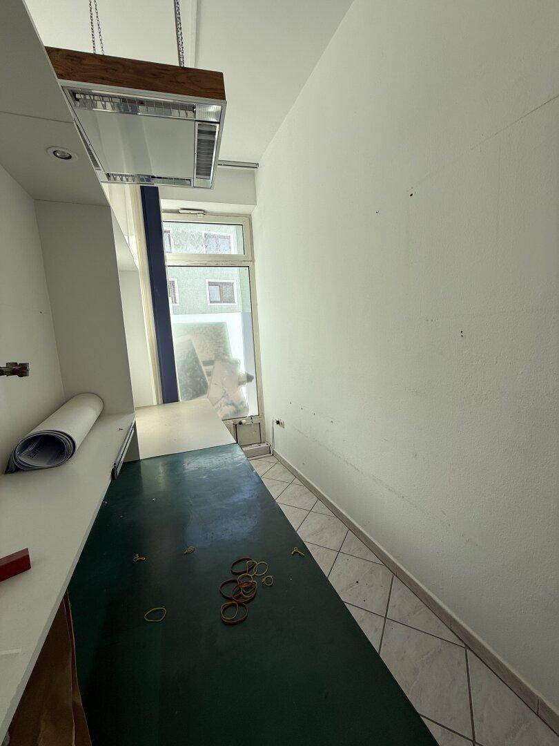 Schmaler Bereich des Büros mit Arbeitsfläche, Fliesenboden und Fenster, ideal für konzentriertes Arbeiten.