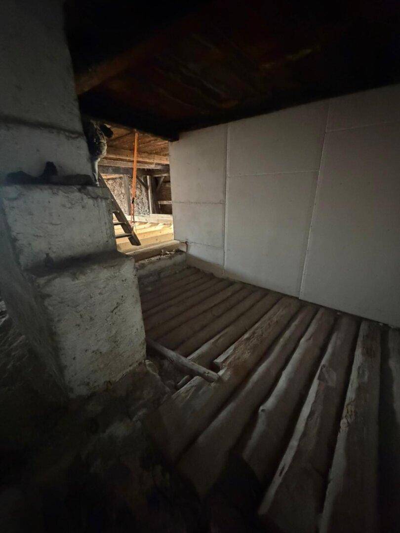 Dachbodenbereich mit Holzboden und freiliegenden Holzbalken, bereit für den Ausbau.