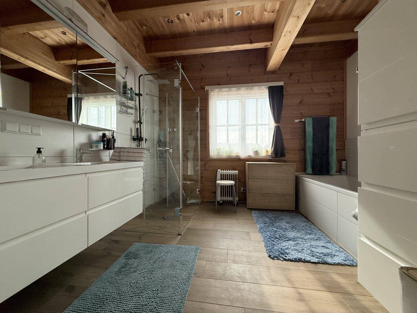Modernes Badezimmer mit Holzbalkendecke, Doppelwaschbecken und großer begehbarer Dusche.