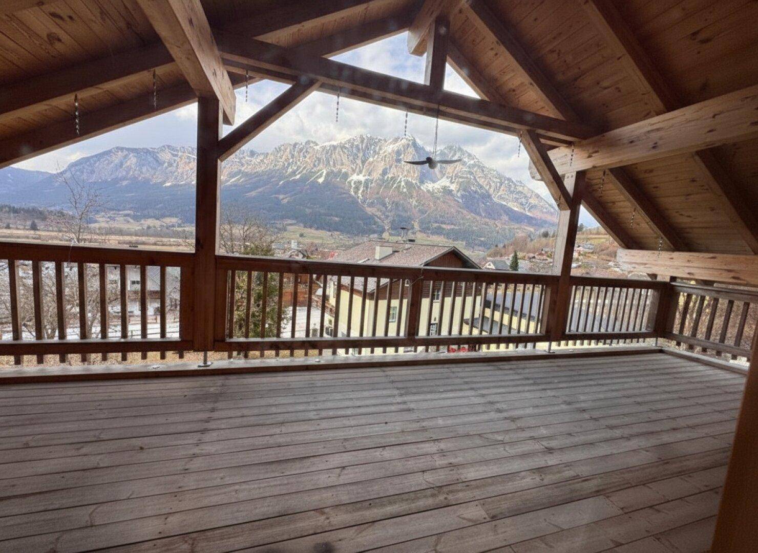 Großer Holzbalkon im Dachgeschoss mit atemberaubendem Blick auf die schneebedeckten Berge.