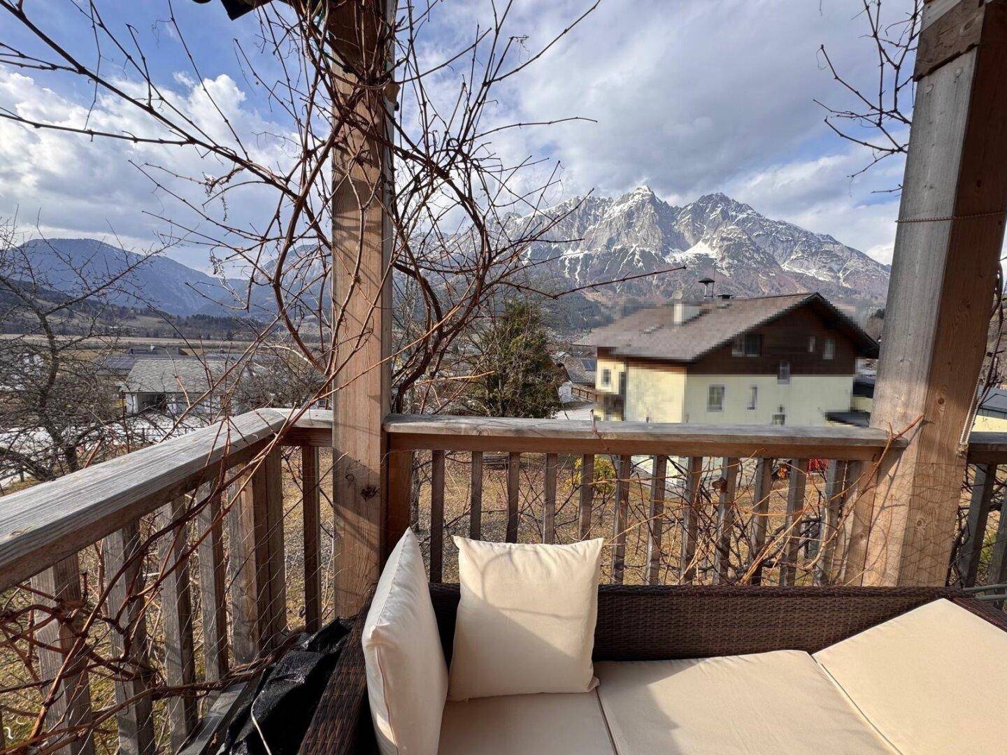 Balkon mit bequemen Sitzmöbeln und weitem Blick auf die schneebedeckten Berge und das Tal.