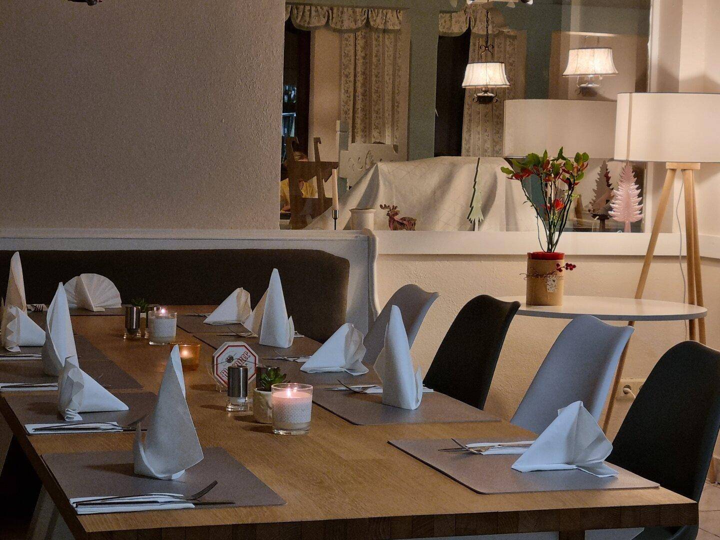 Gemütlicher Essbereich mit einem langen Holztisch, festlich gedeckt mit weißen Servietten und Kerzenlicht.