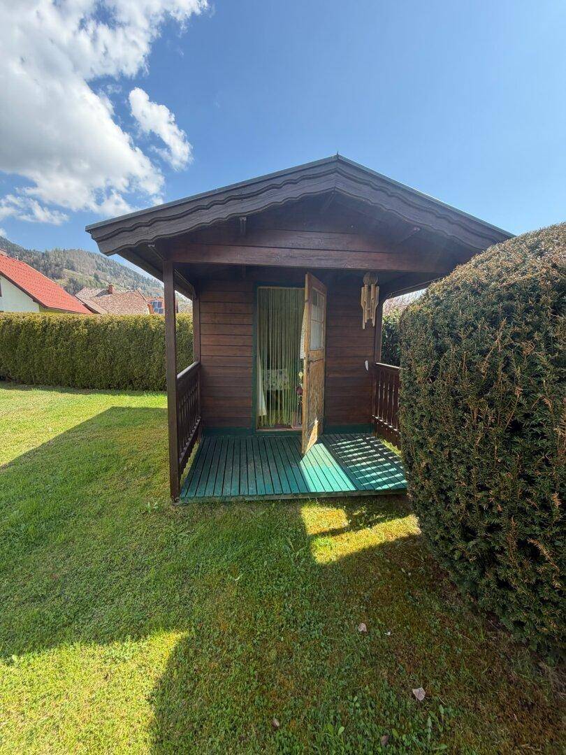 Kleiner, rustikaler Holzschuppen mit Veranda und Blick auf die umliegende Natur.