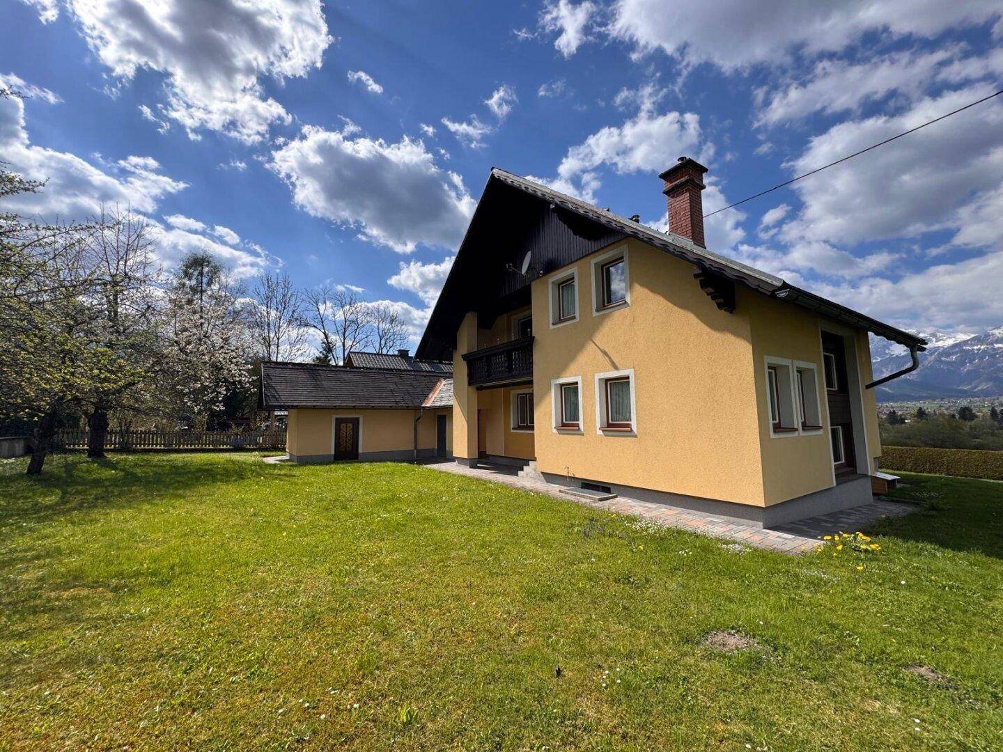 Geräumiges Grundstück mit Einfamilienhaus und weitläufiger Rasenfläche unter sonnigem Himmel.