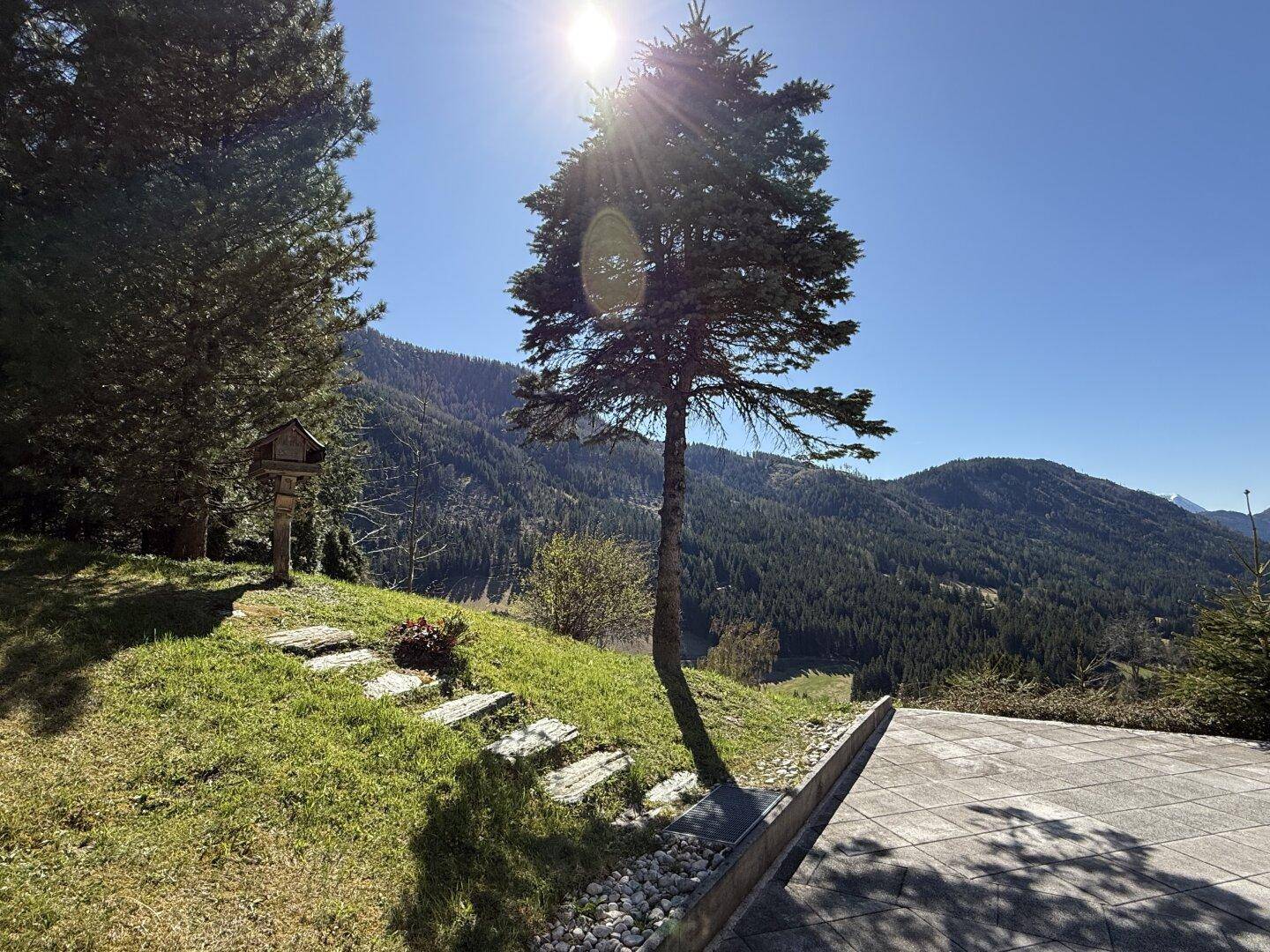 Sonniger Außenbereich mit Steinstufen und weitem Blick auf die bewaldeten Berge.