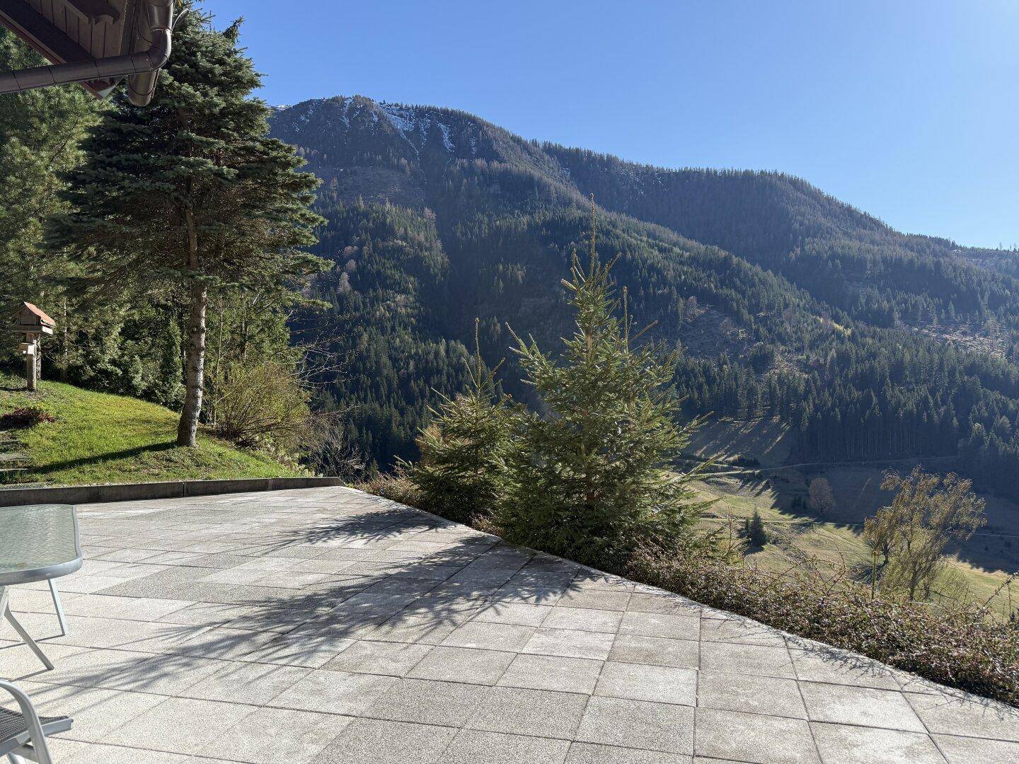 Geräumige gepflasterte Terrasse mit Sitzgelegenheiten und Panoramablick auf die umliegenden Berge.