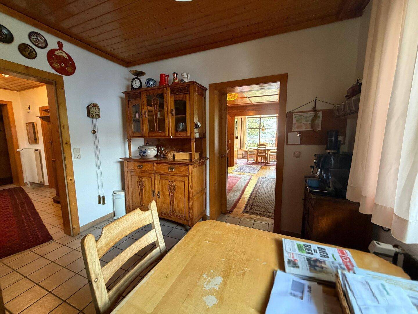 Traditioneller Flur mit Holzmöbeln und Durchgang zu einem weiteren Wohnbereich.