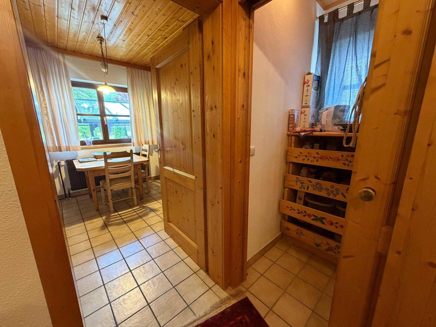 Kleiner Flur mit Holztüren und Zugang zu einem Essbereich mit Fenster.