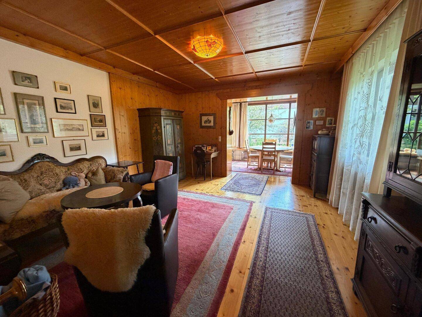 Gemütliches Wohnzimmer mit Holzboden, traditionellen Möbeln und Blick in den Garten.