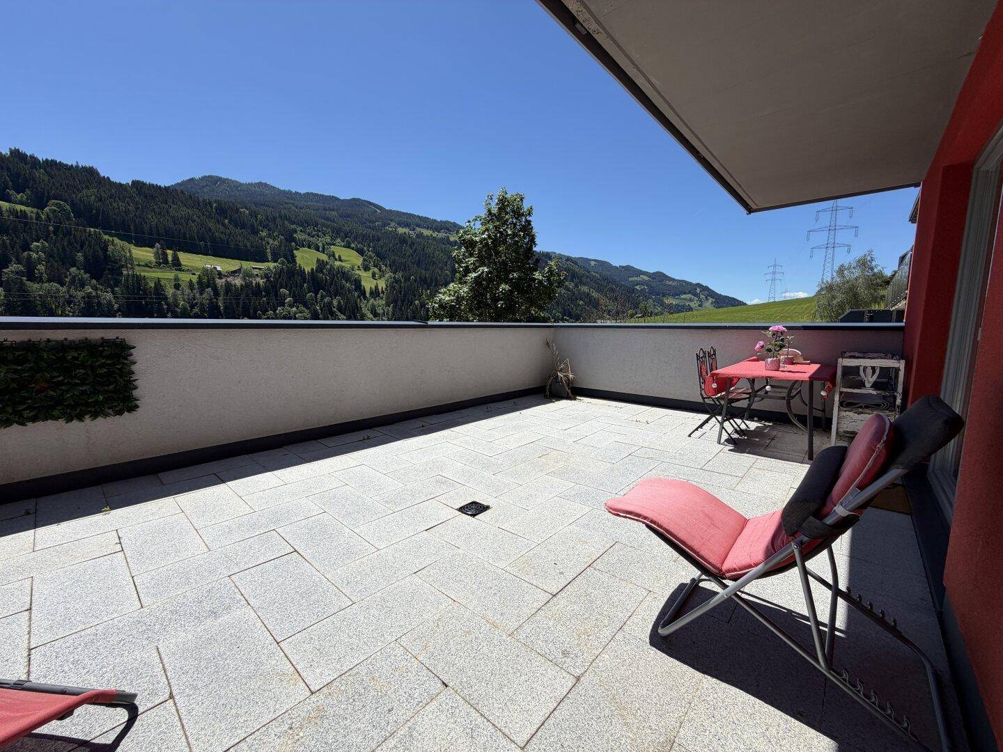 Helle Terrasse mit Esstisch und Liegestuhl, bietet einen schönen Blick auf die Natur.
