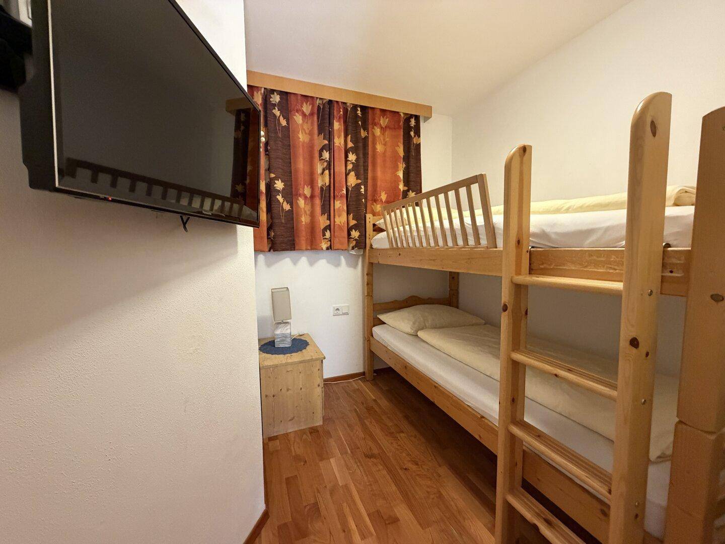 Kleines Schlafzimmer mit Etagenbett und Holzboden, ideal als Kinder- oder Gästezimmer.