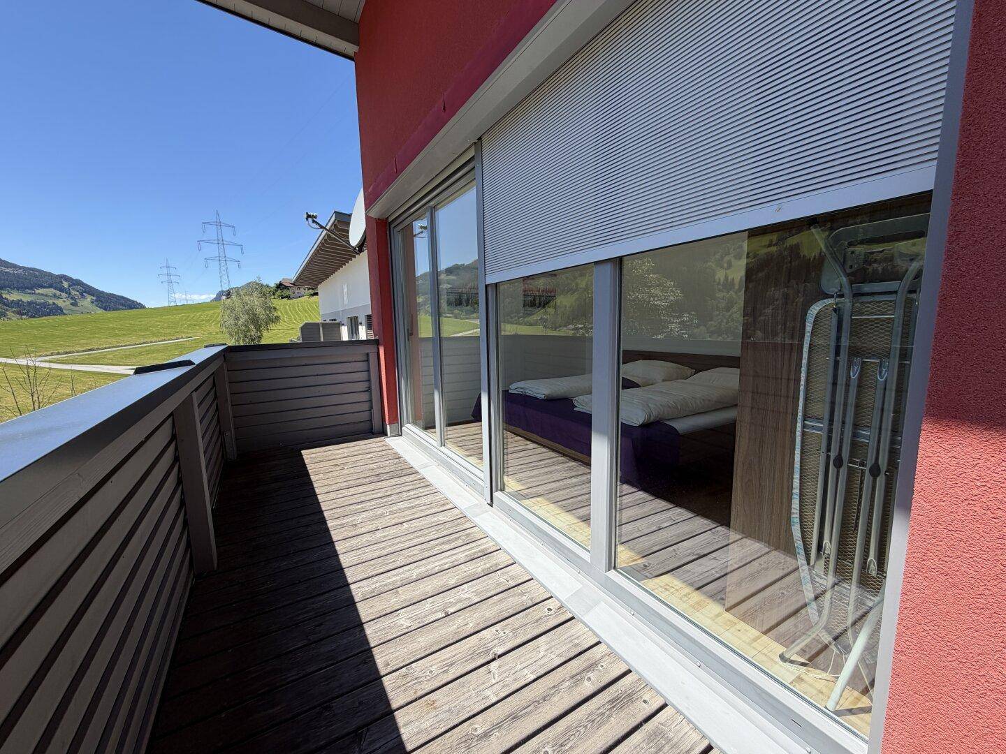 Schmaler Balkon mit Holzboden und Blick auf die grüne Umgebung, ideal für frische Luft.
