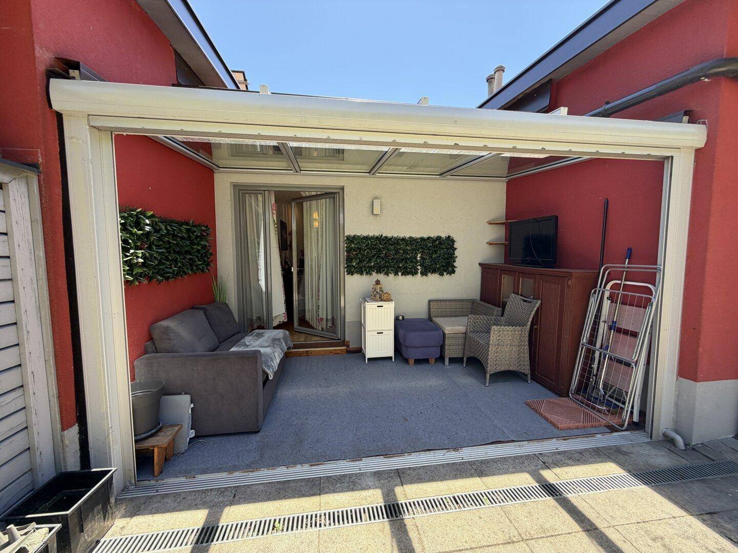 Gemütlicher Wintergarten mit Sofa und Fernseher, ideal zum Entspannen bei jedem Wetter.