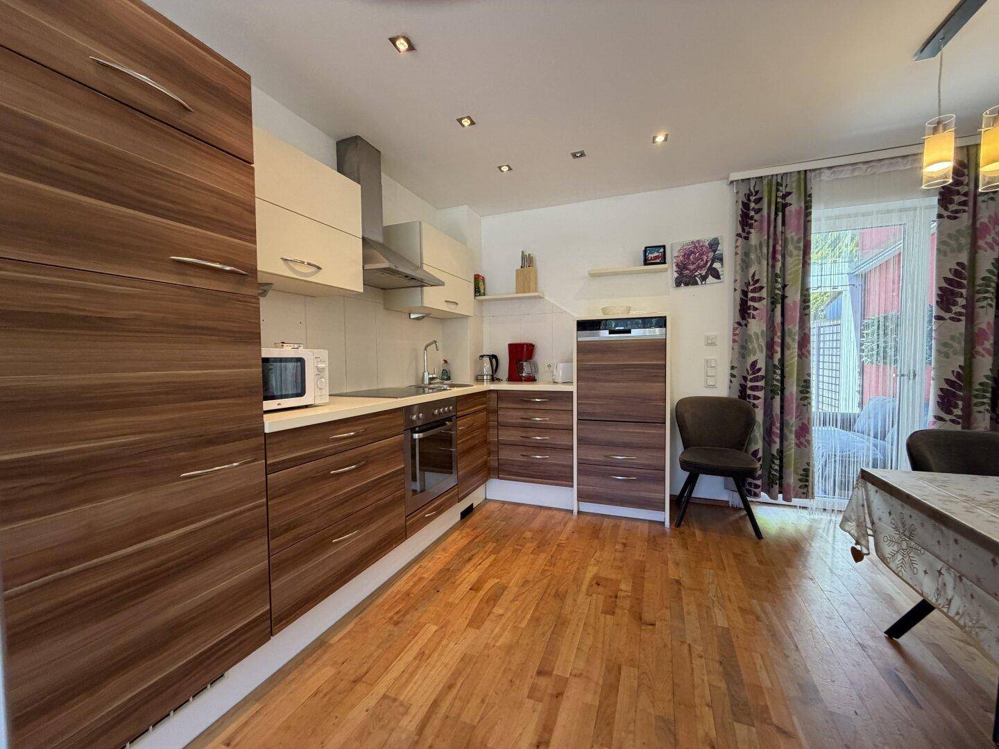 Moderne Einbauküche mit Holzelementen, integrierten Geräten und Essbereich, offen gestaltet.