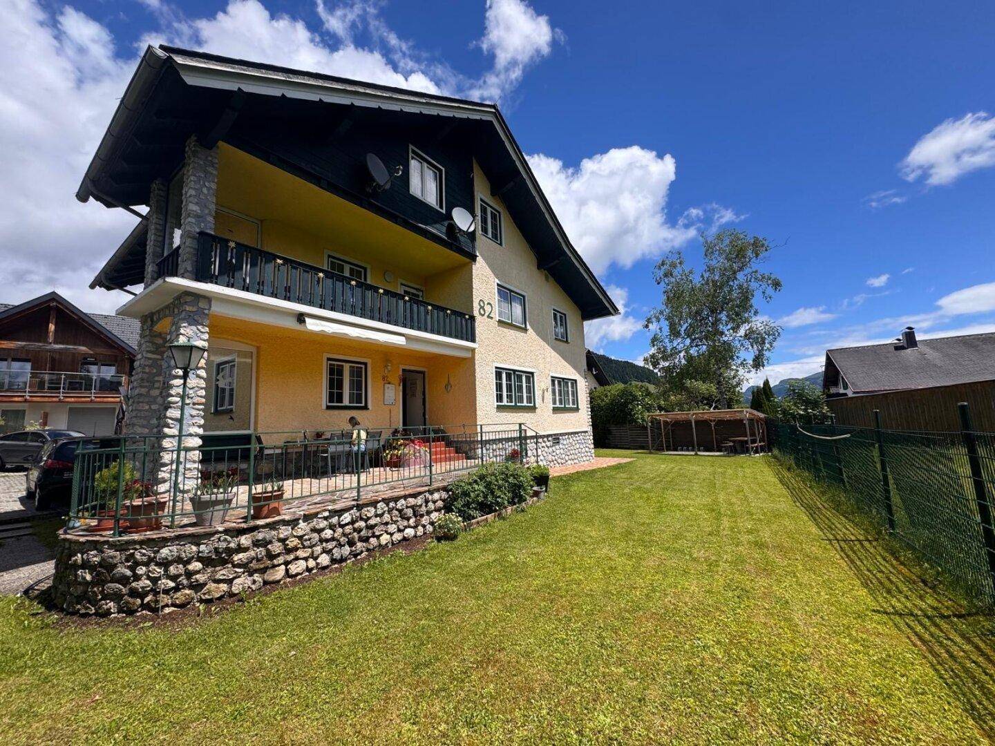 Großzügiger Gartenbereich vor dem Haus mit gepflegtem Rasen und Blick auf die Berge.