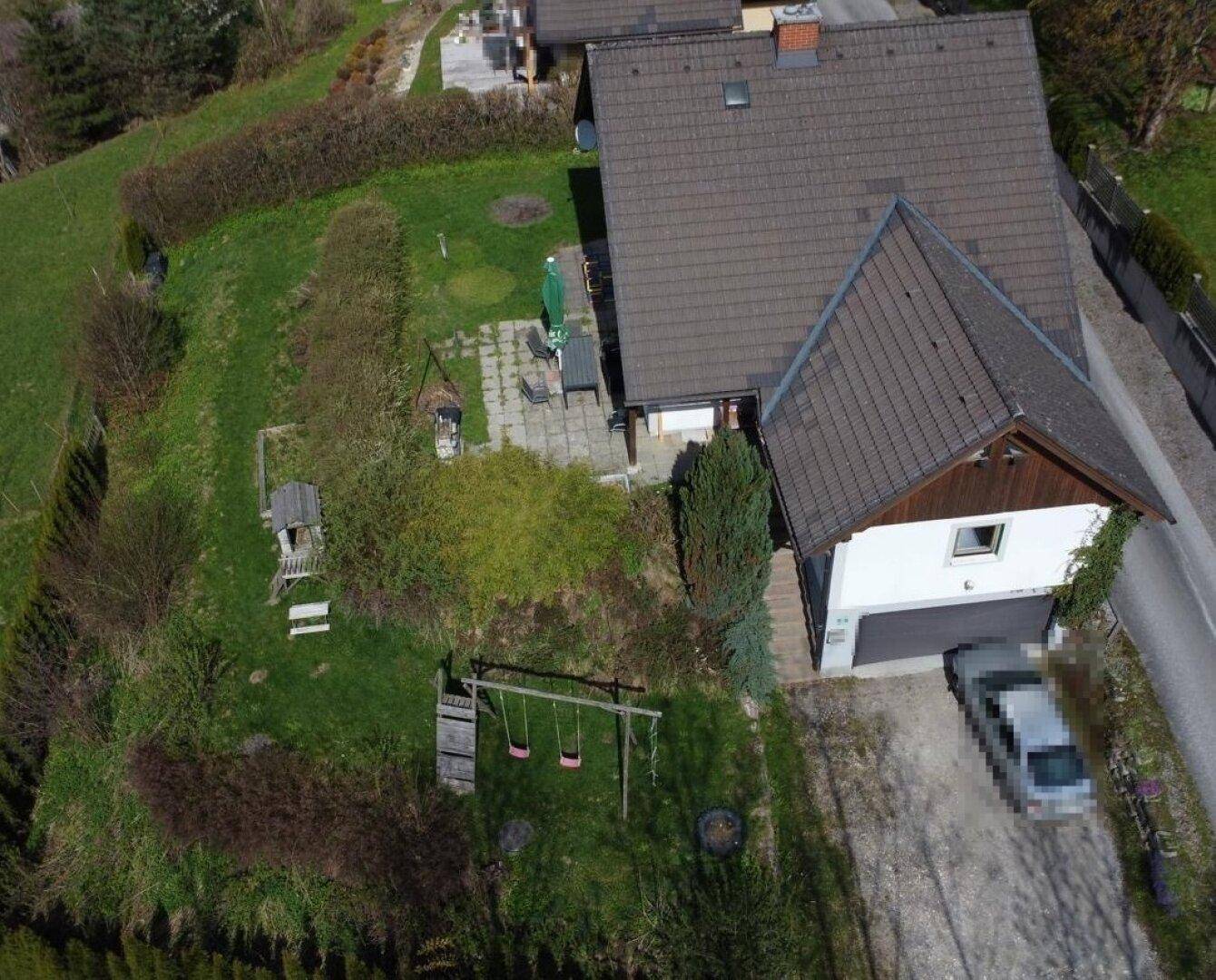Luftaufnahme eines Einfamilienhauses mit großem Garten, Terrasse und Kinderspielplatz.