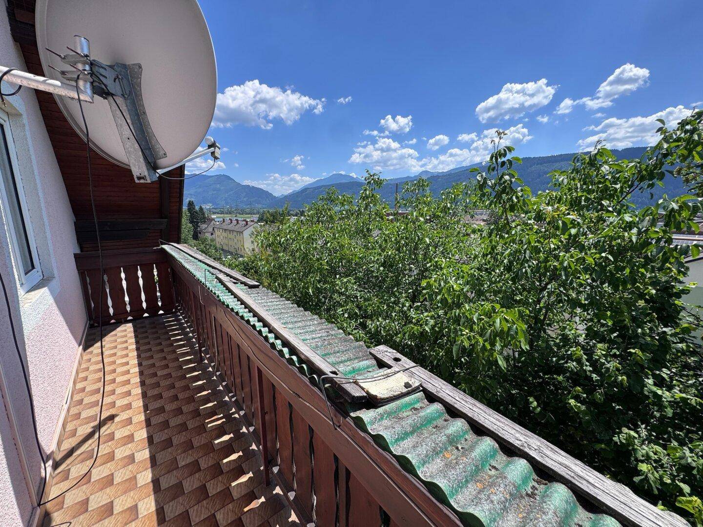 Balkon mit Fliesenboden und Holzgeländer bietet einen weiten Blick auf die Berge und die Umgebung.