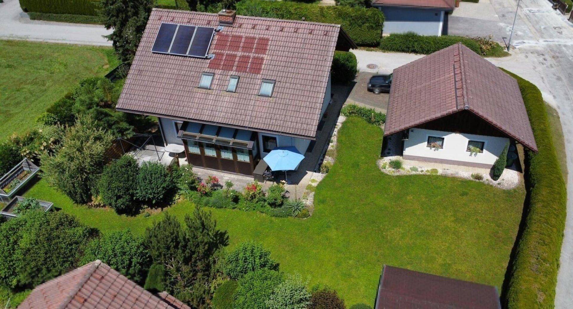 Vogelperspektive eines Hauses mit gepflegtem Garten, Terrasse und Solaranlage auf dem Dach.