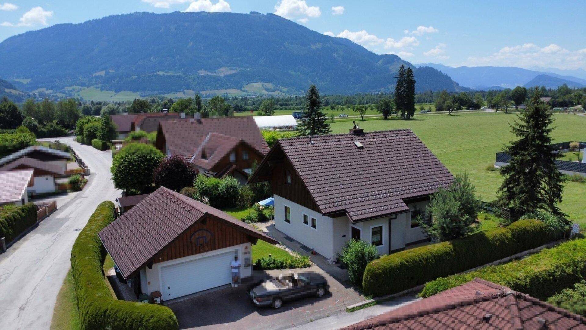 Einfamilienhaus mit Garage und gepflegter Auffahrt in einer ländlichen Umgebung mit Bergblick.