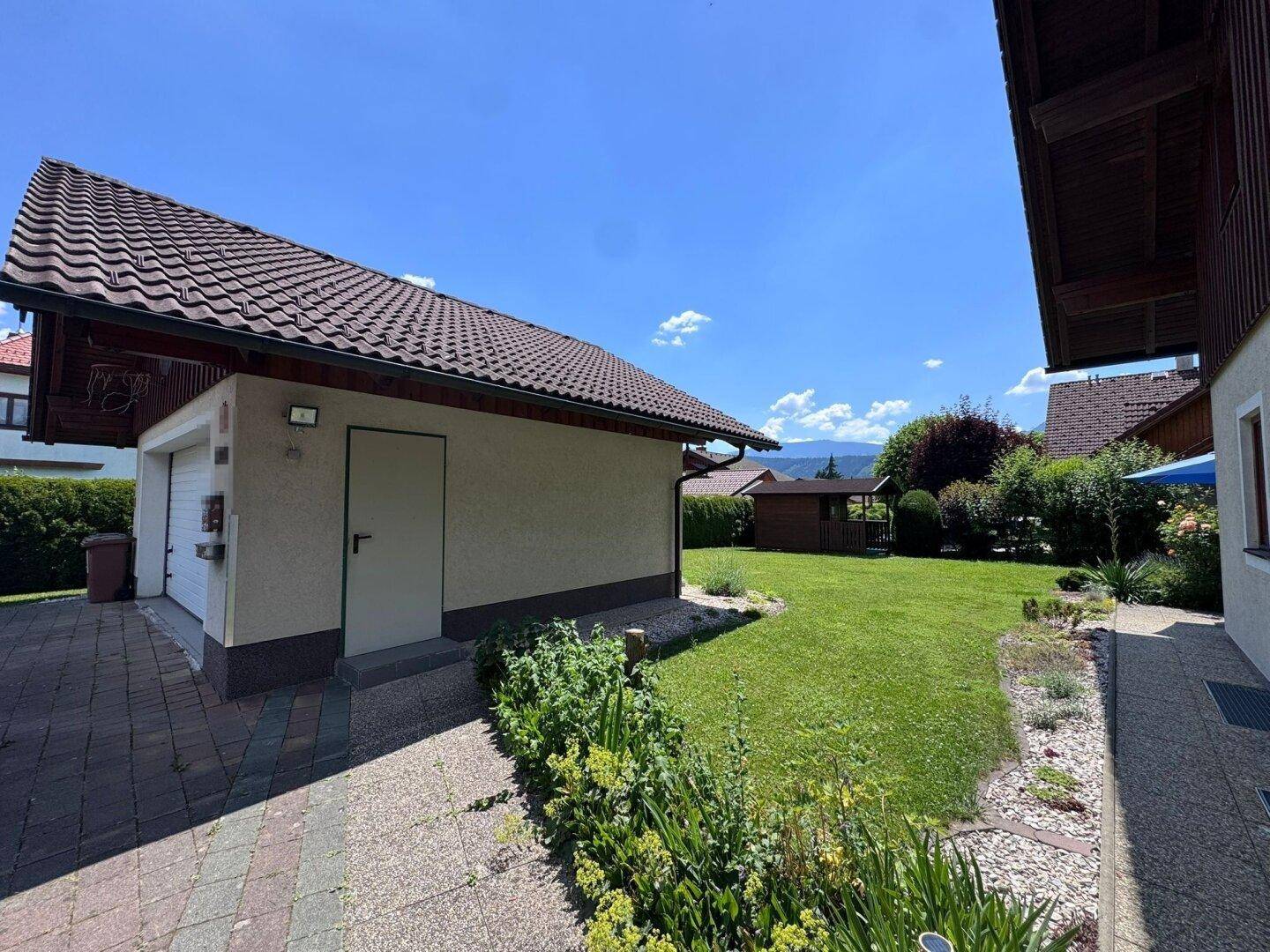 Freistehende Garage mit gepflegtem Rasen und gepflasterter Zufahrt.