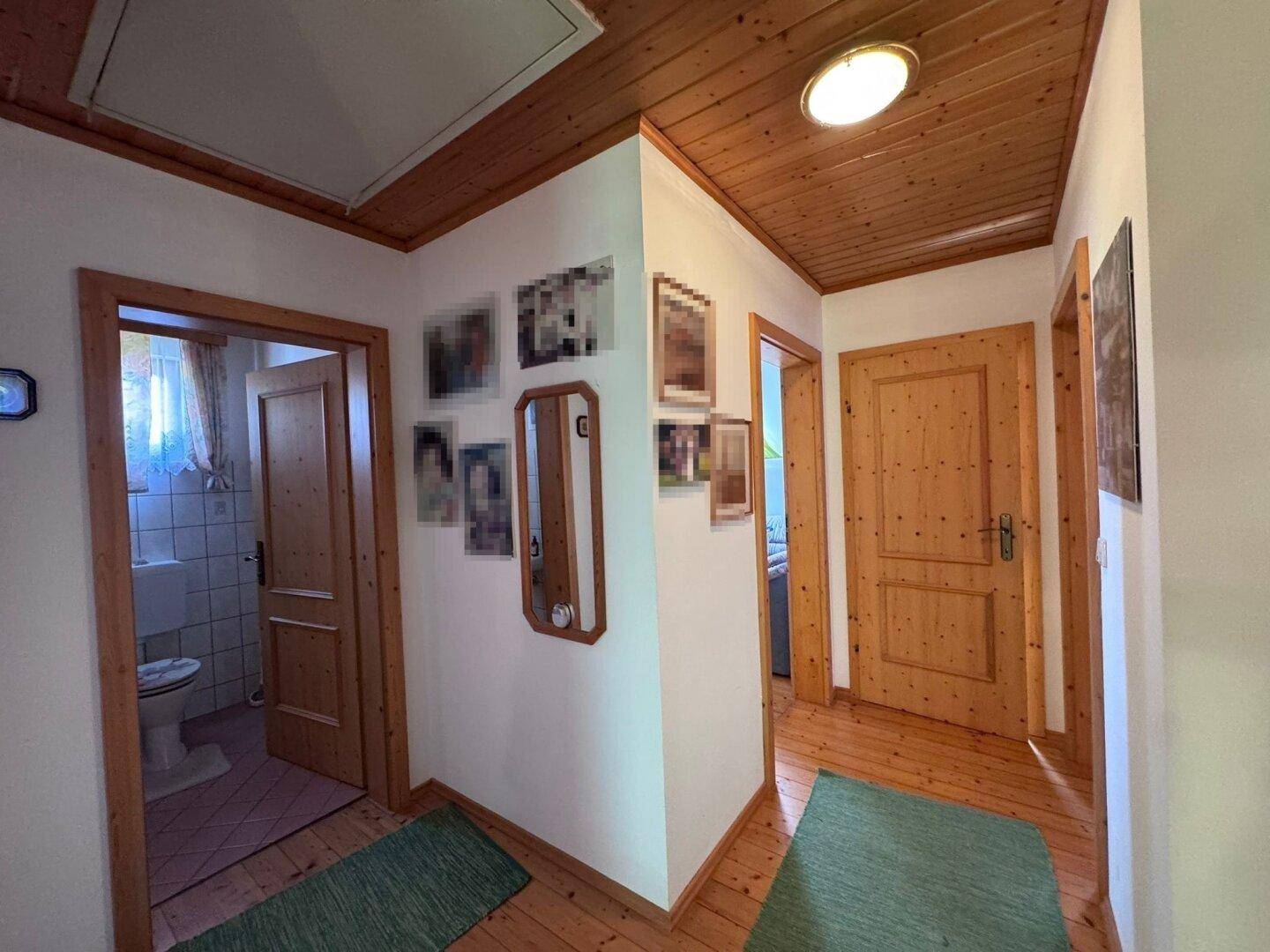 Heller Flur mit Holzdecke, Holztüren und Parkettboden, der zu weiteren Räumen führt.