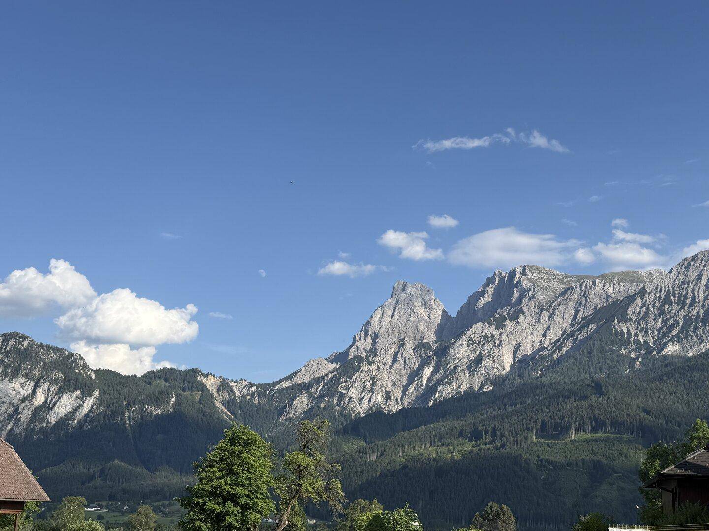 Majestätische, felsige Bergkette unter einem strahlend blauen Himmel mit vereinzelten Wolken.
