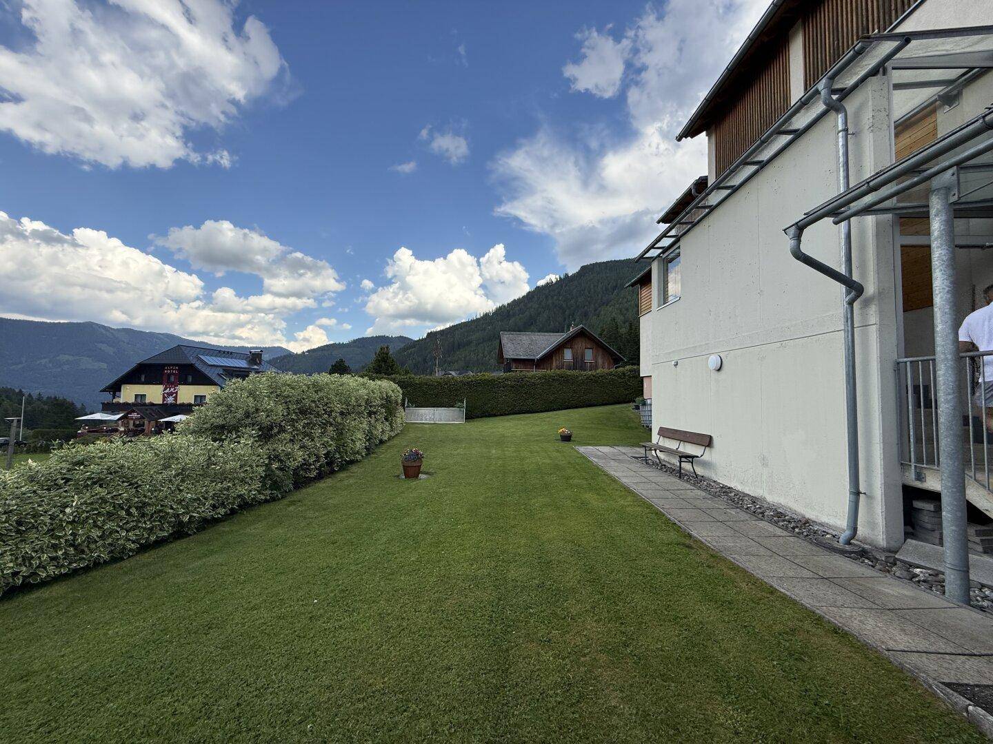 Großer, gepflegter Rasenbereich neben dem Haus mit Blick auf die umliegende Berglandschaft.