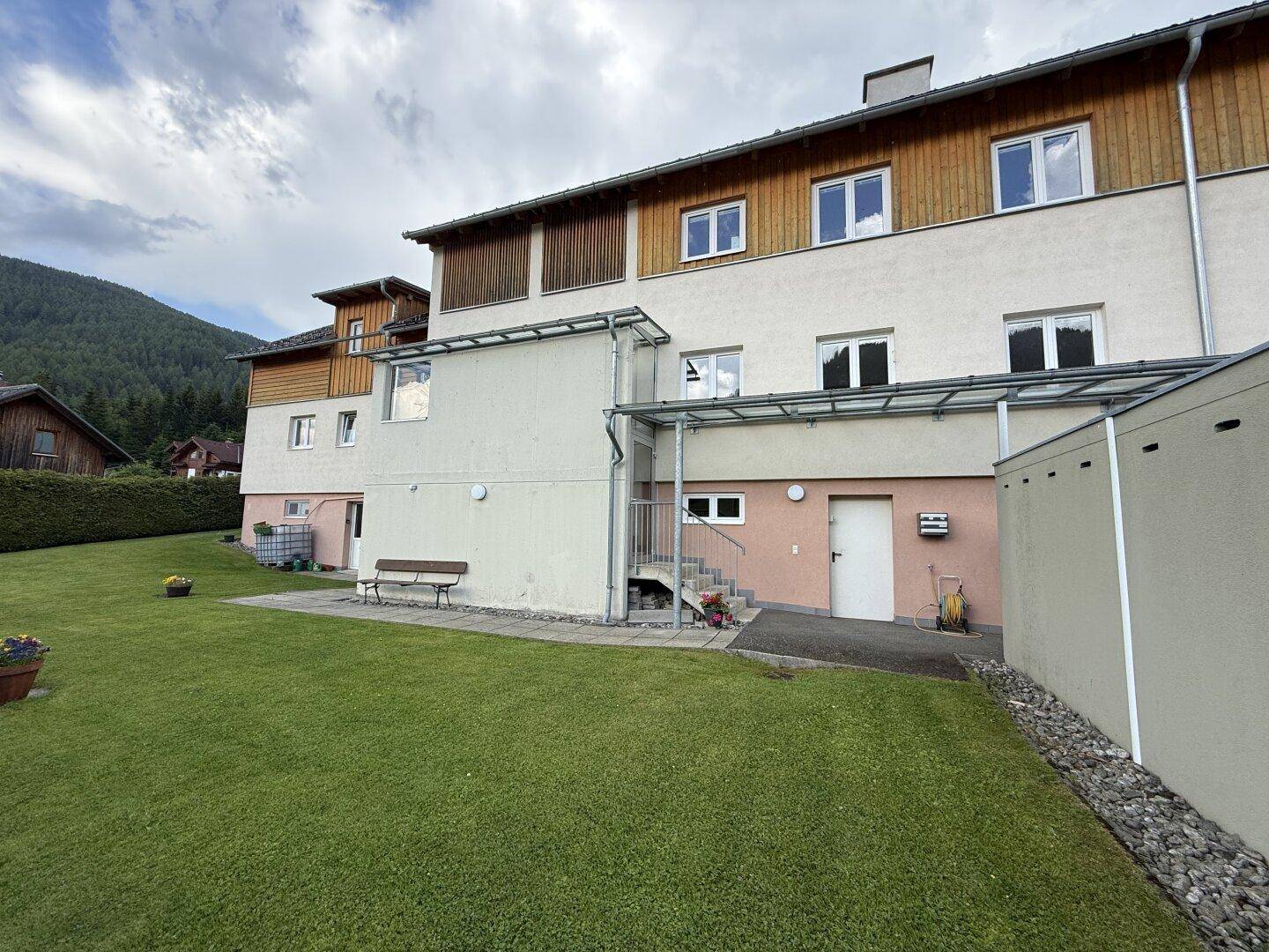 Rückseite des Gebäudes mit Zugang zum Garten und einer kleinen Terrasse.