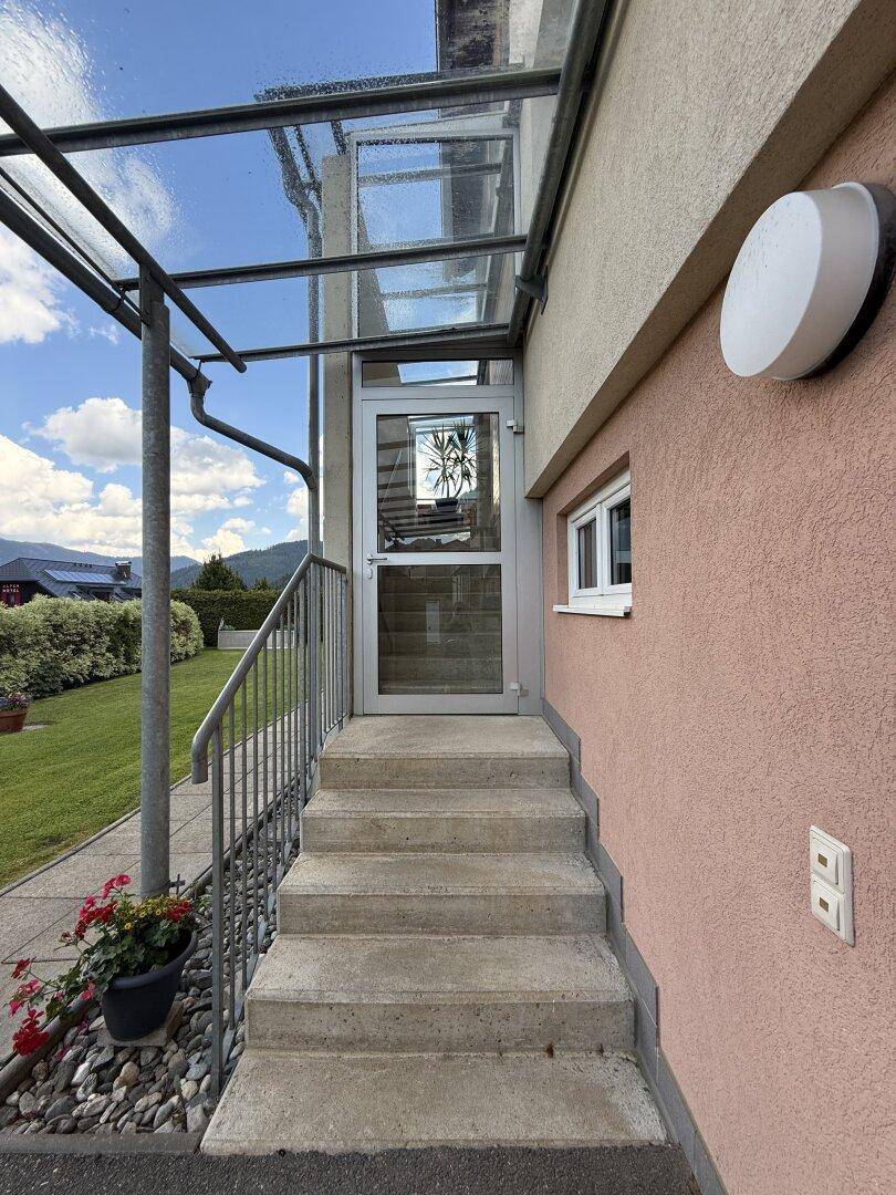 Eingangsbereich des Hauses mit überdachter Treppe und Metallgeländer.