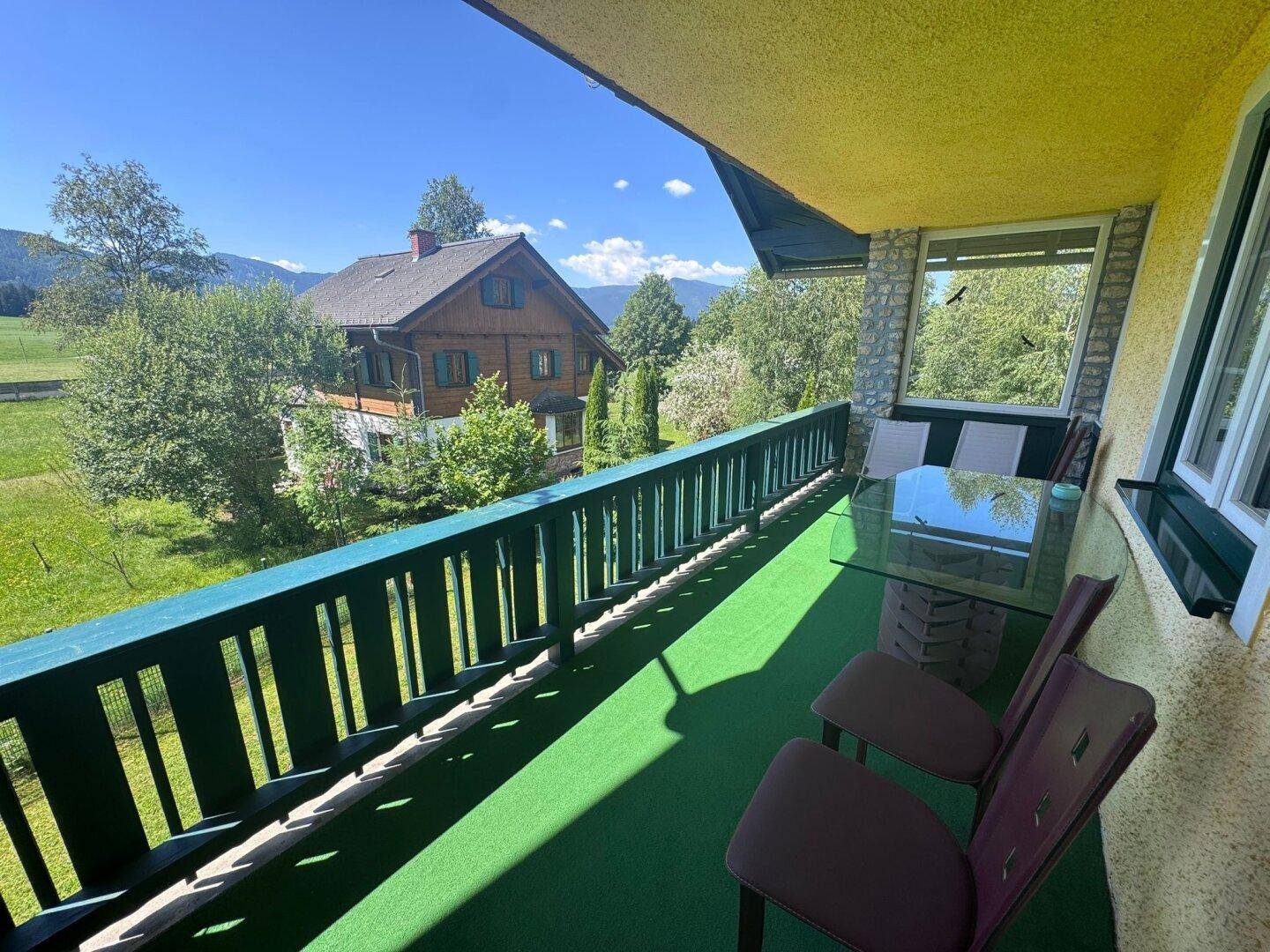 Möblierter Balkon mit Kunstrasen und weitem Blick auf die umliegende Natur und Berge.