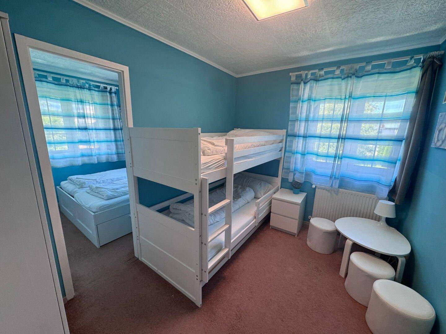 Kinderzimmer mit Etagenbett, Einzelbett und blauen Wänden, ideal für Familien.