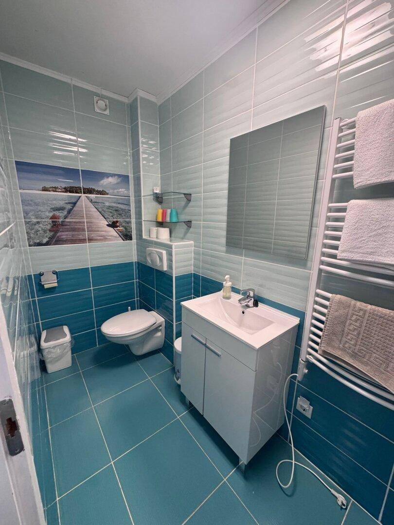 Modernes Badezimmer mit blauen Fliesen, WC, Waschbecken und beheiztem Handtuchhalter.