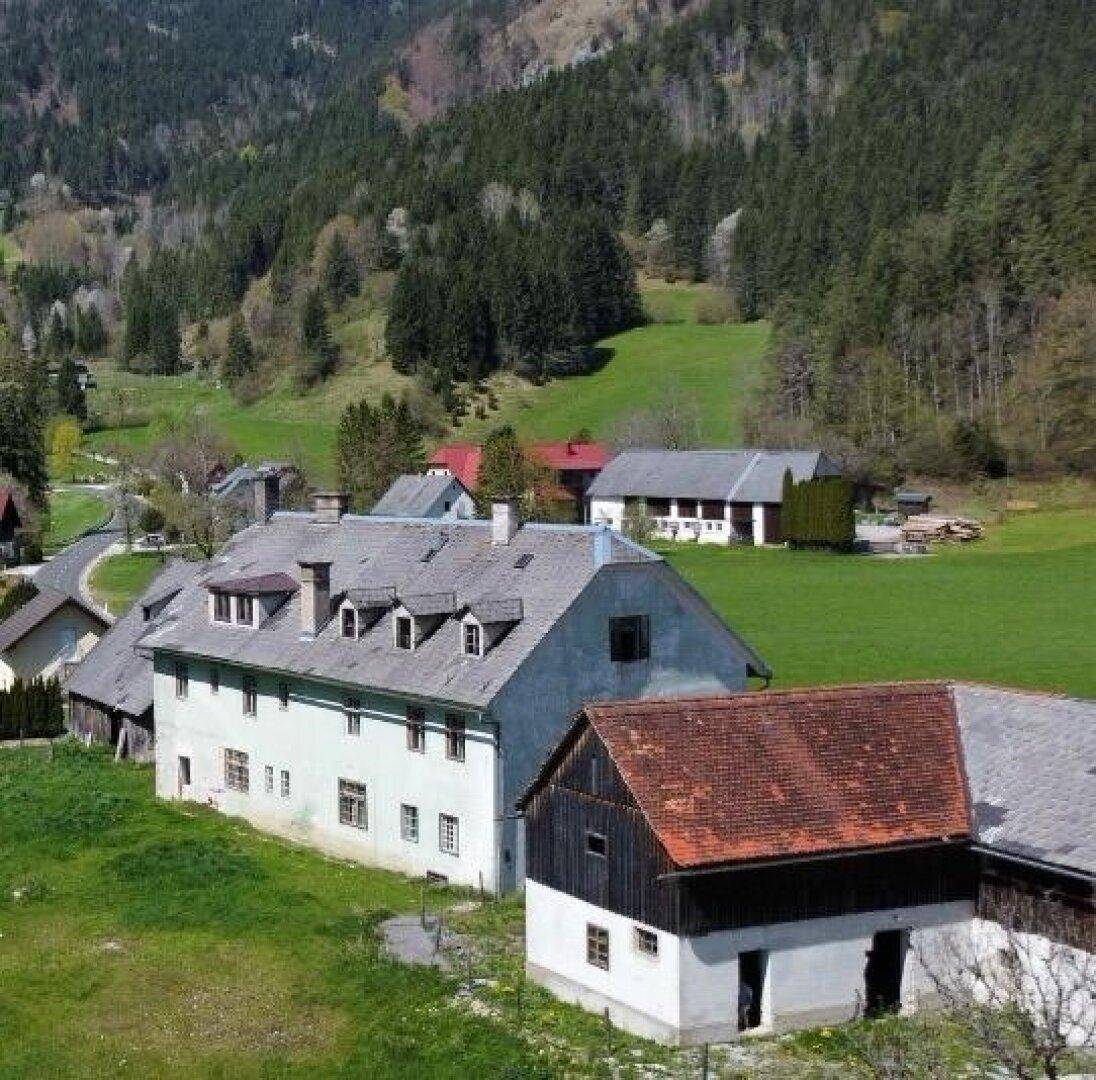 Historisches Anwesen in ländlicher Umgebung mit Blick auf bewaldete Berge und grüne Täler.
